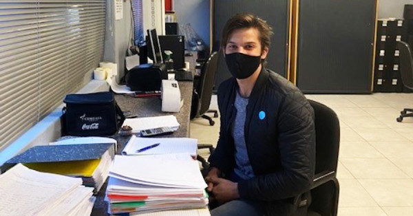 man with mask doing paperwork at desk