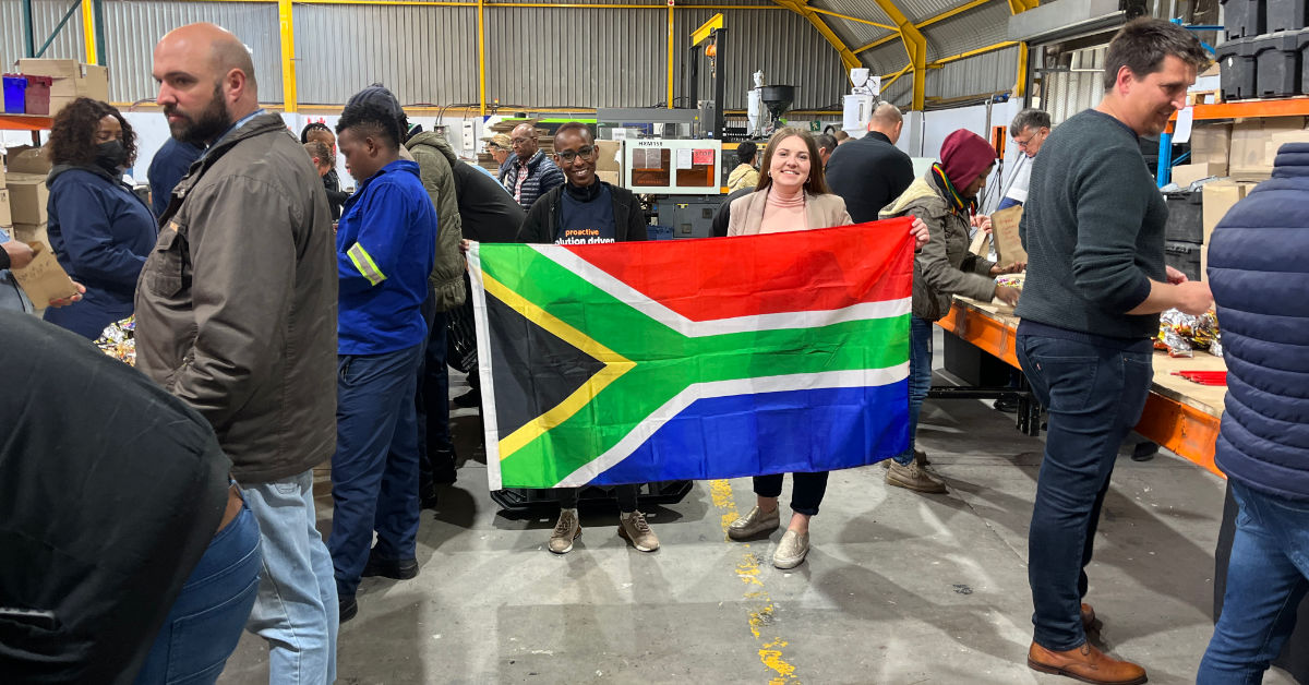 Woman holding south african flag at work in factory