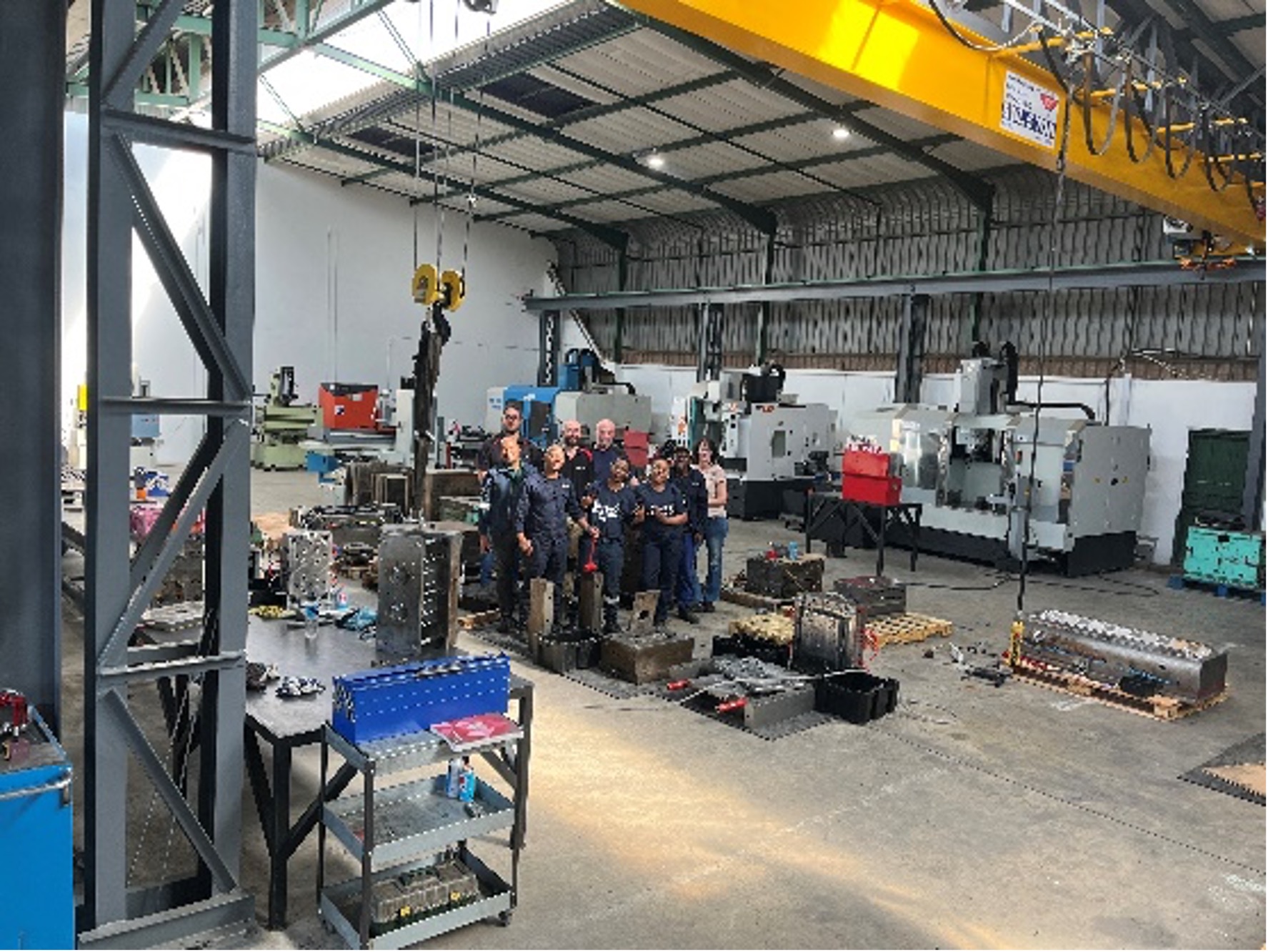 Group of employees in the factory with machinery